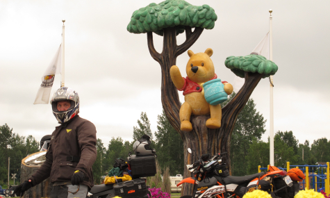 motorcycle rider with motorcycles standing in front of winnie the pooh and tree statue