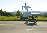 motorcycle riding past giant white goose monument